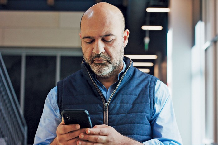 A man in a laboratory hallway looking at his cell phone. A man in a laboratory hallway looking at his cell phone.