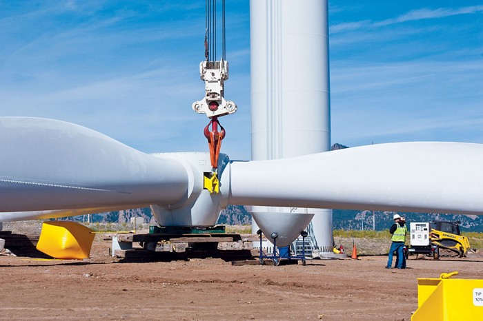 This image shows people and machinery moving a large wind turbine blade. 09615-cover1-turbinebladecxd.jpg