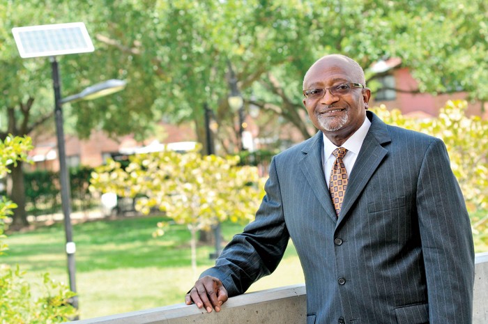 A man in a photograph with a college campus behind him.