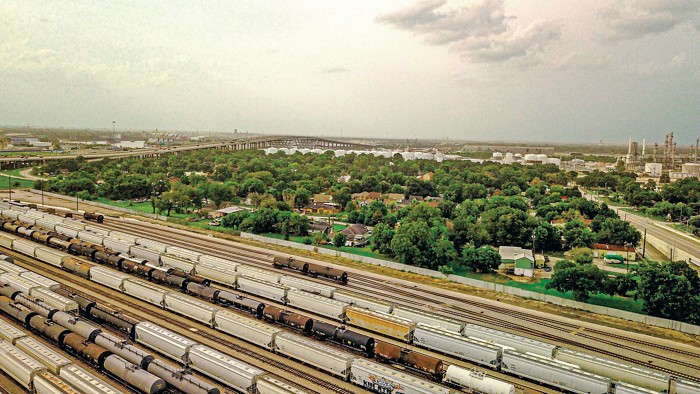 Aerial view of a town surrounded by highway, industry, and rail tracks on a ship channel.