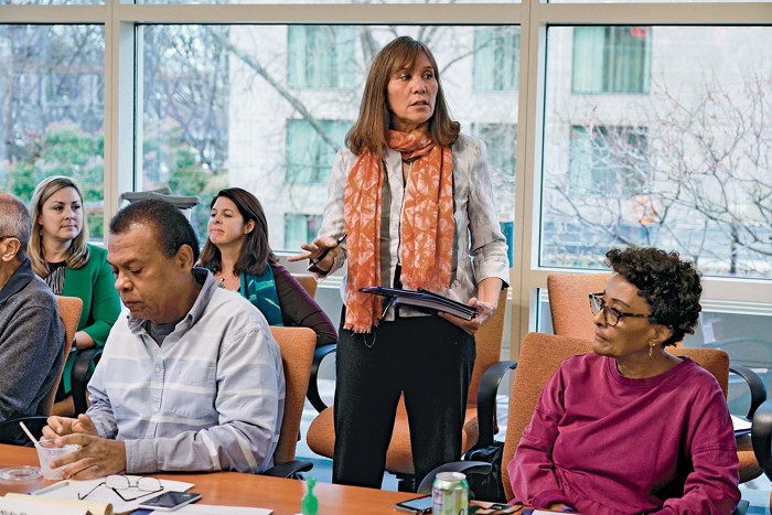 A photo of a woman addressing people in a conference room.