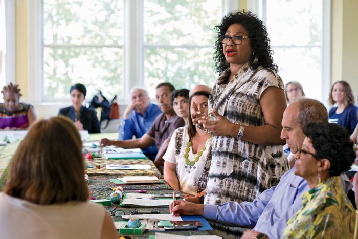 A photo of a woman addressing people in a conference room.