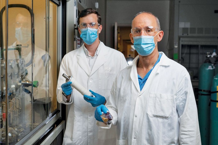 A photo of scientists holding a membrane module and a vial of polymer. 09835-feature1-opener.jpg