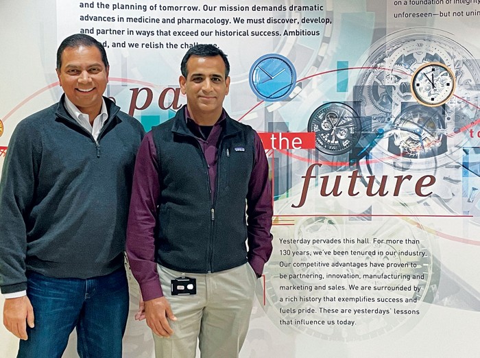Two pharmaceutical research executives standing in front of a promotional display.